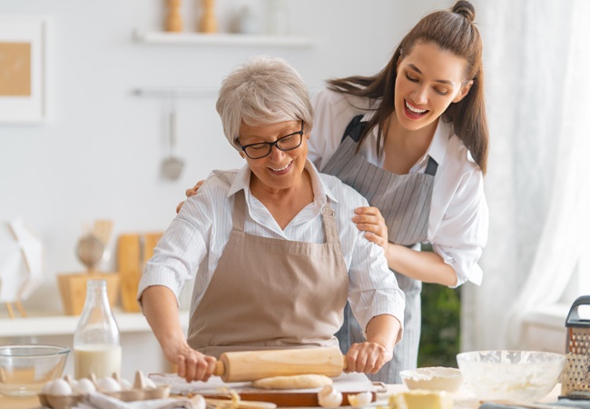 2 femmes dont une âgée qui cuisinent et rient ensemble