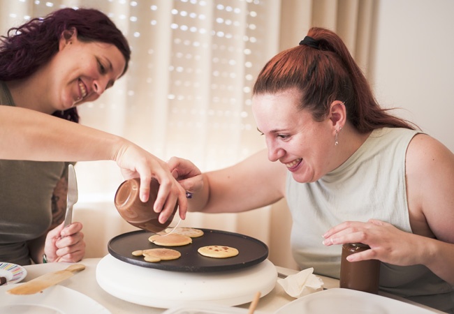 2 femmes font des pancakes ensemble et rigolent