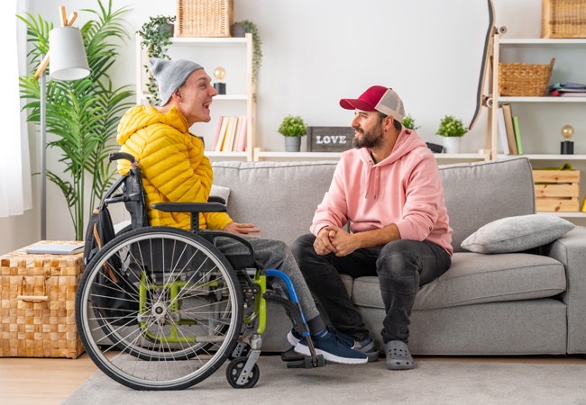 Aidant qui discute avec un jeune homme en situation de handicap