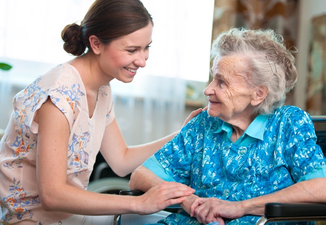 Aide à domicile qui discute avec une femme âgée en souriant