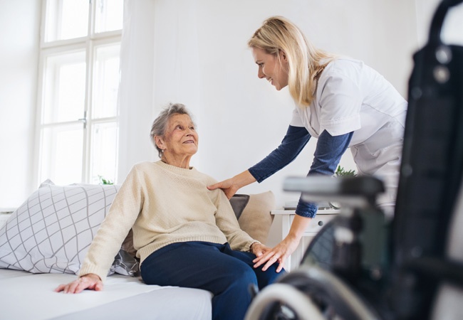 Dame qui aide une personne âgée à se lever pour aller dans son fauteuil