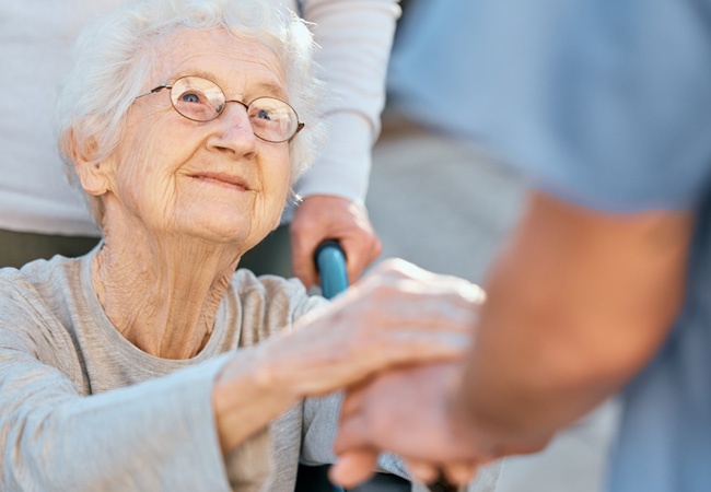 Femme âgée souriante qui tient la main d'un infirmier