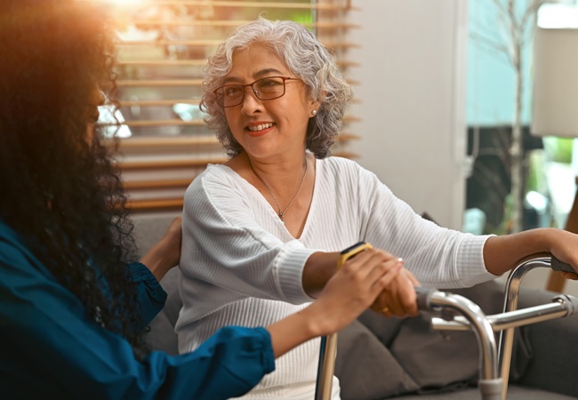 femme qui aide une personne avec deambulateur à se lever