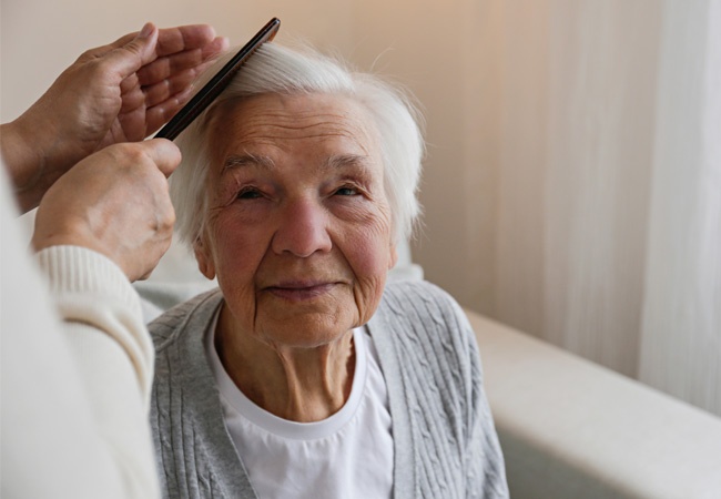 Femme qui coiffe une dame âgée heureuse