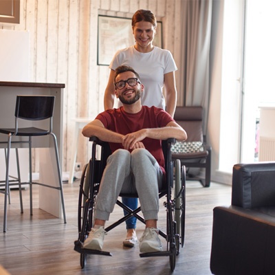 Femme qui pousse un homme en fauteuil roulant