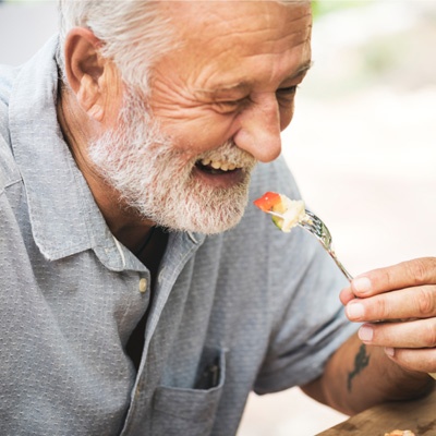 Monsieur âgé qui mange en souriant