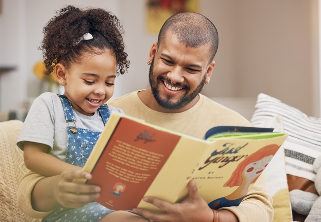 Père et petite fille qui lisent un livre et rigolent ensemble