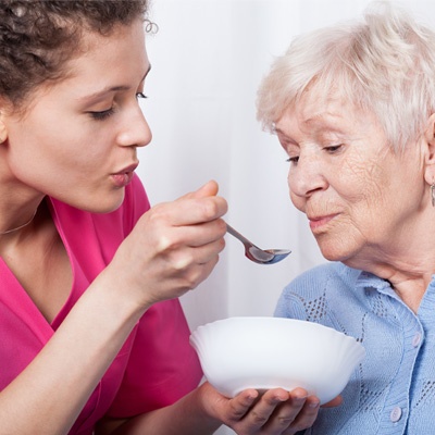 Soignante qui donne à manger à une dame âgée