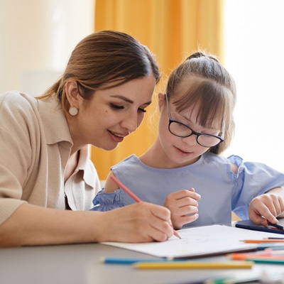 enfant atteinte de trisomie 21 qui apprend à colorier