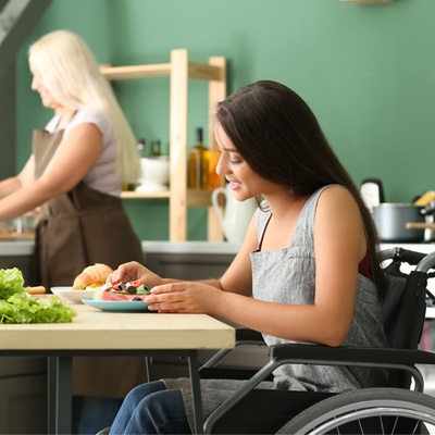 Une femme qui aide une femme en fauteuil à cuisiner dans sa cuisine