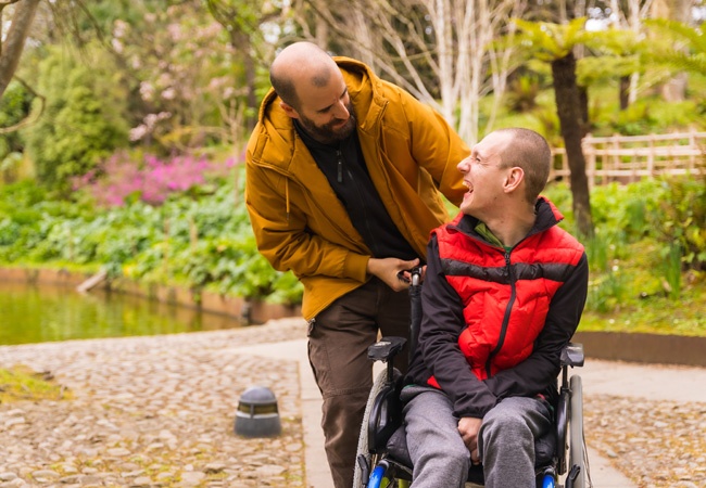 Un homme et une personne en situation de handicap rigolent et discute