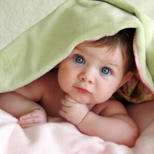 Un bébé caché sous une couverture qui regarde devant lui