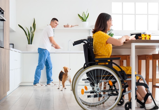 Un homme fait la vaisselle et aide une jeune femme en fauteuil