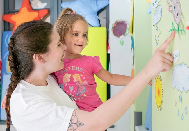 Une accompagnatrice qui montre une forme à un enfant heureux