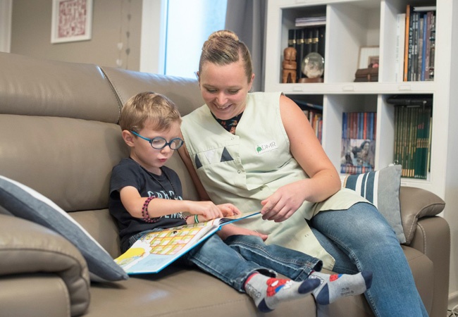 Une aide à domicile qui aide un petit garçon à lire