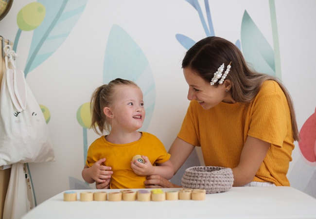 Une dame qui joue avec une enfant trisomique