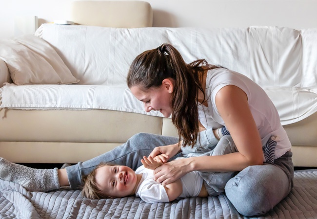 Une femme joue et rigole avec un bébé atteint de la trisomie