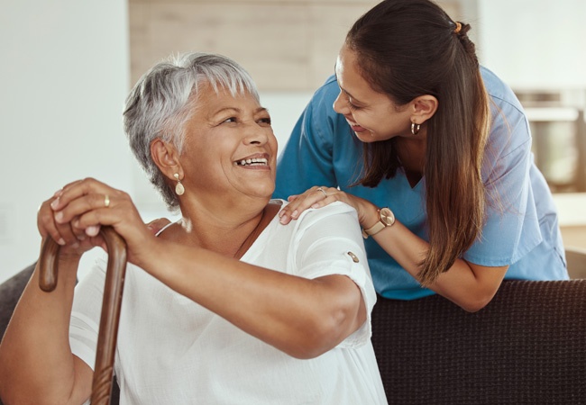 Une soigannte et une dame âgée qui sourient et discutent