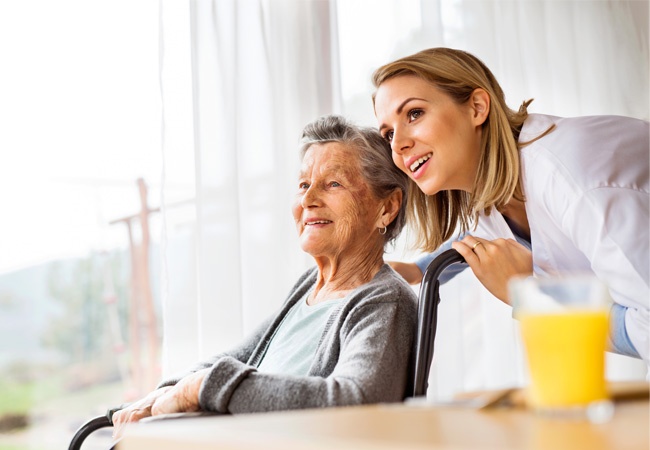 Une soignante et une dame âgée qui regardent par la fenetre