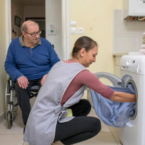 aide à domicile qui s'occupe du linge d'un homme âgé