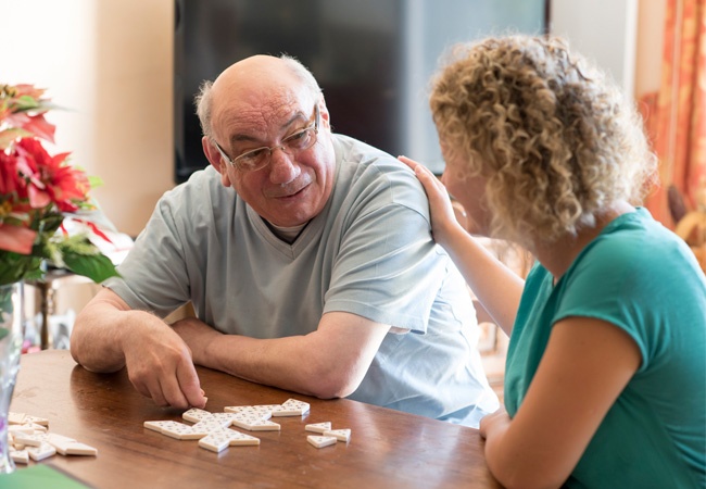 dame qui aide un monsieur âgé à faire un jeu