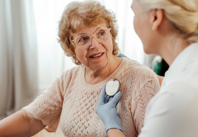 medecin qui montre un stimulateur cardiaque à une dame dans son salon