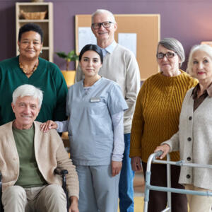 soignante entourée d'un groupe de seniors qui sourient