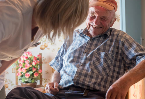 soignante fait un soin à un monsieur âgé souriant