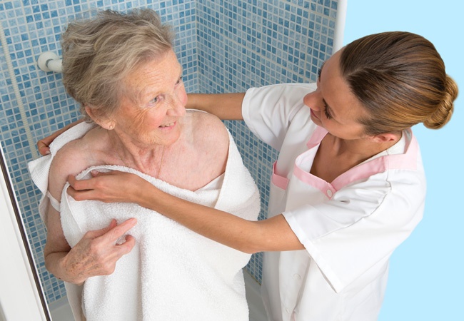 soignante qui aide à la douche d'une femme âgée