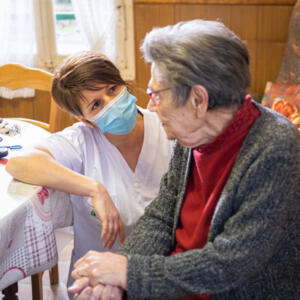 soignante qui parle avec une dame âgée dans son salon