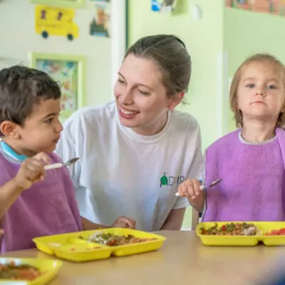 Aide ADMR qui aide des enfants à manger à la crèche