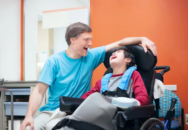 Un homme qui rigole avec un garçon handicapé